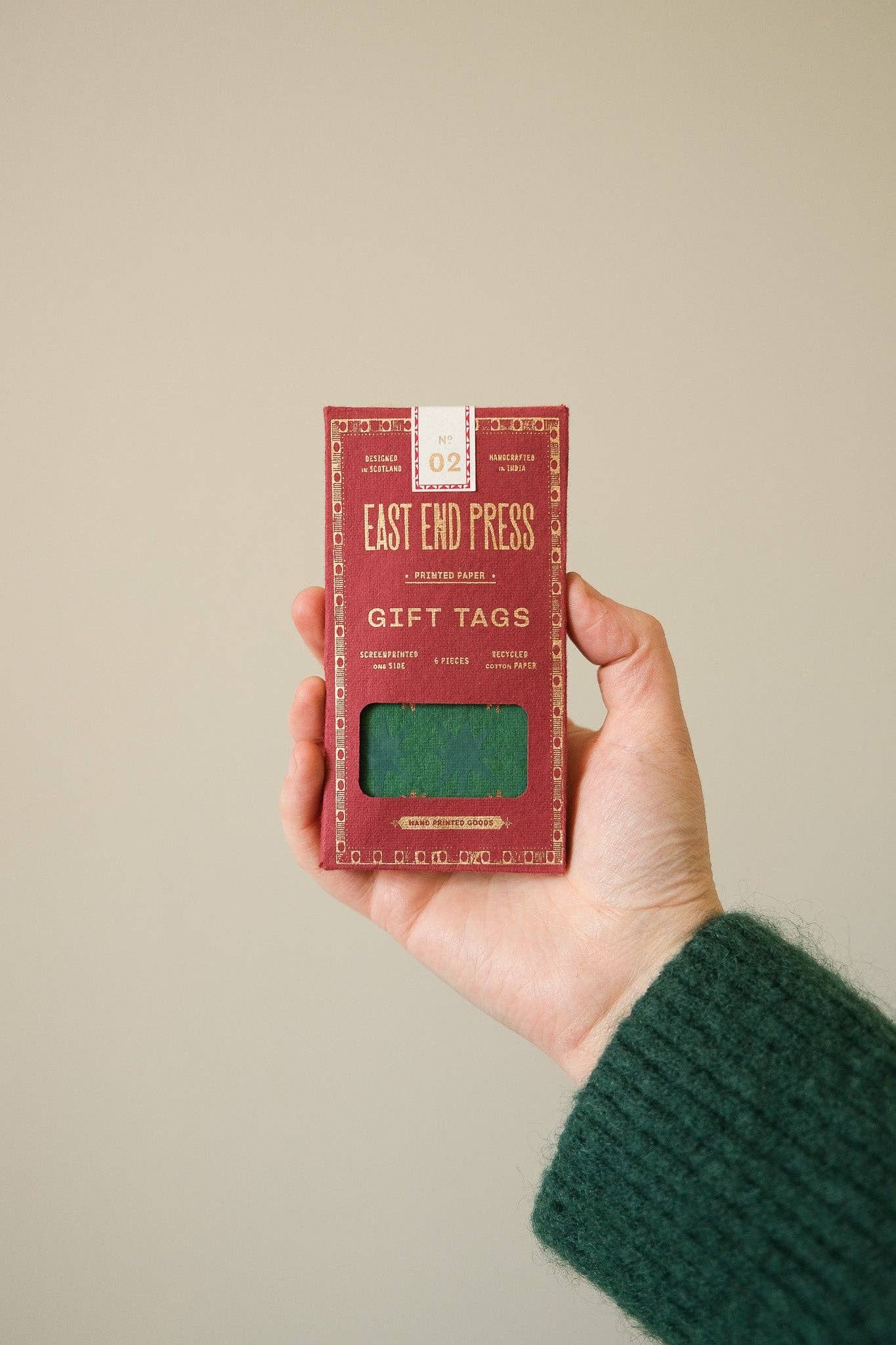 Hand holding a box of East End Press gift tags against a beige background