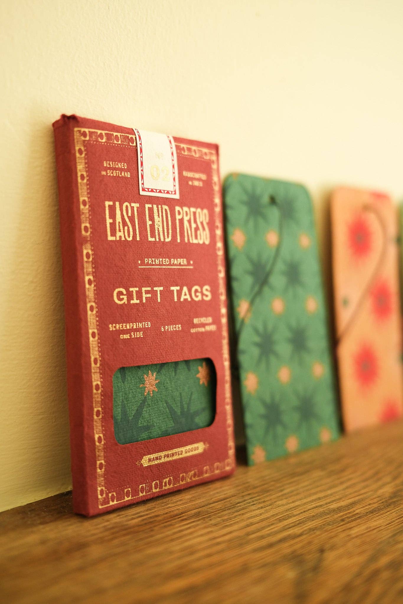 Pack of East End Press gift tags on a wooden shelf with other colorful items.