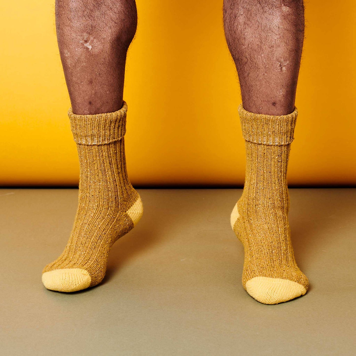 Yellow socks worn on feet against a yellow background
