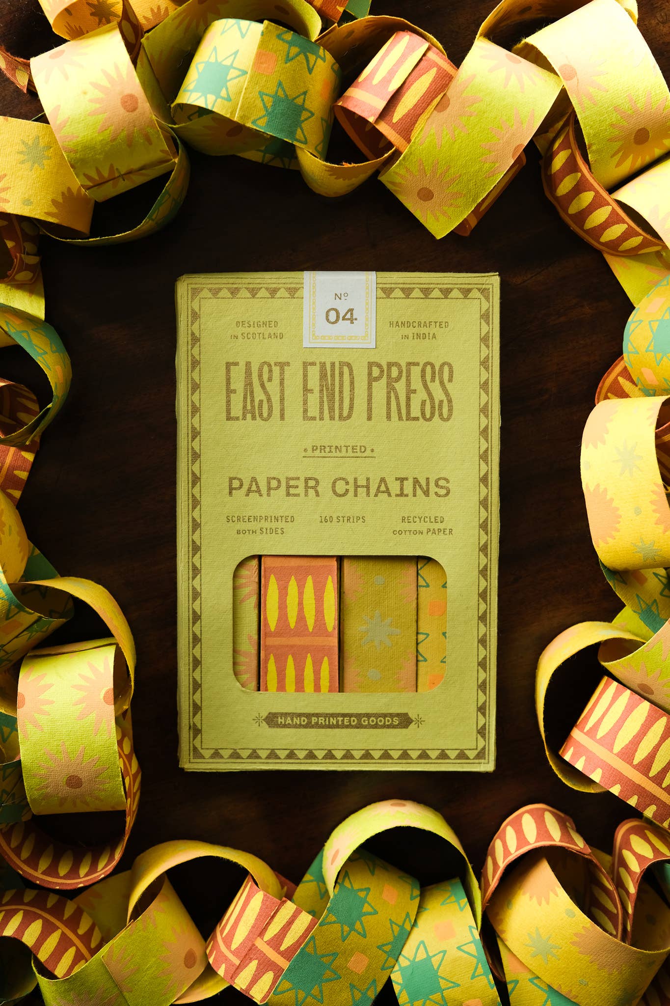 Pack of East End Press paper chains surrounded by colorful paper chains on a dark background