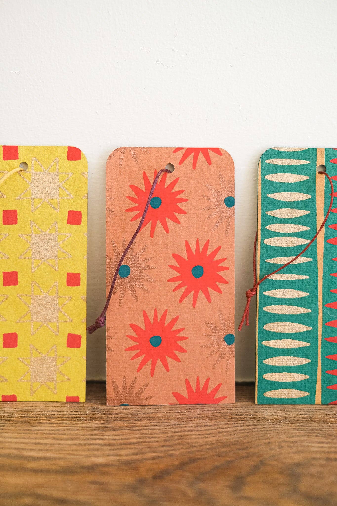 Three colorful phone cases with floral and geometric patterns on a wooden surface.
