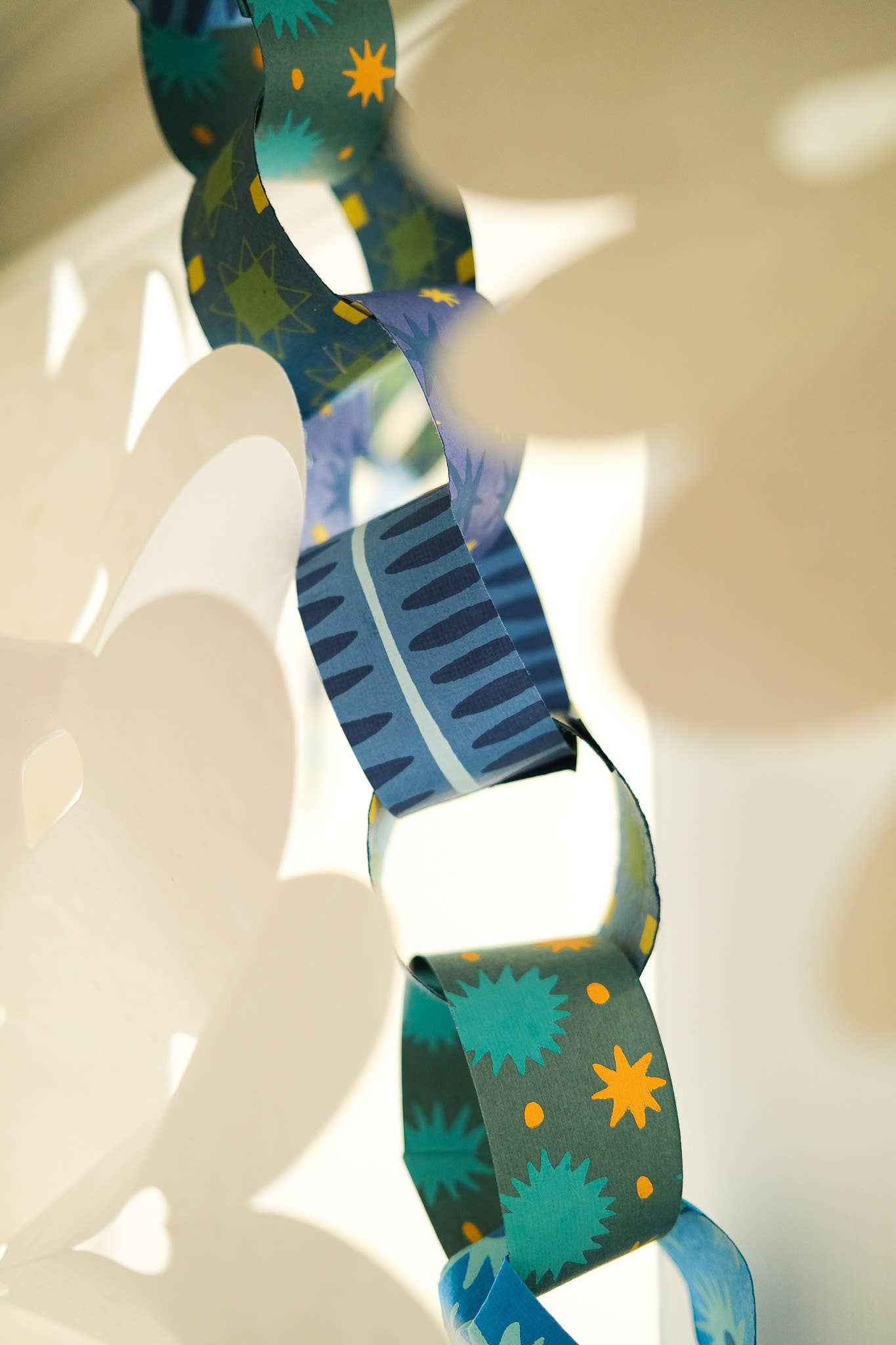Colorful paper chain with geometric patterns on a white background