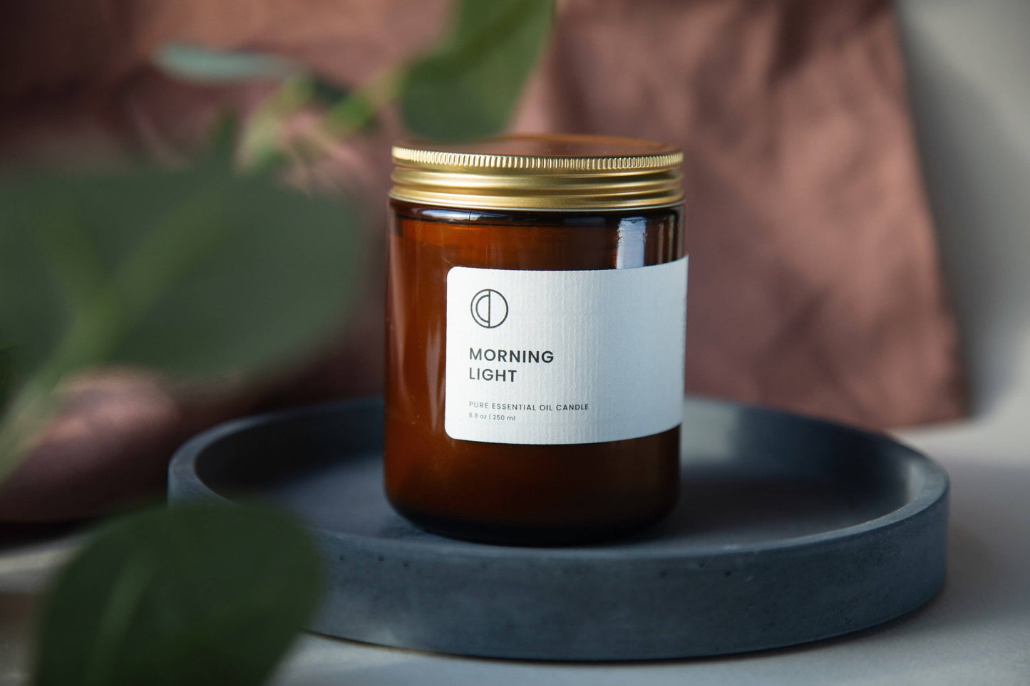 Candle labeled 'Morning Light' on a gray surface with a blurred background