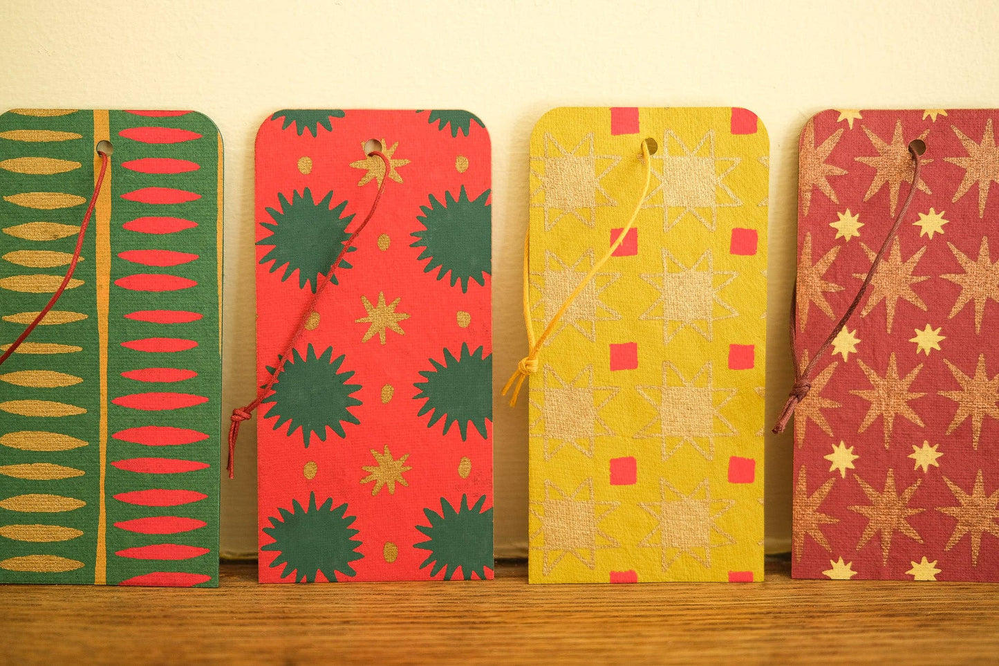 Four colorful patterned notebooks with decorative ribbons on a wooden surface.