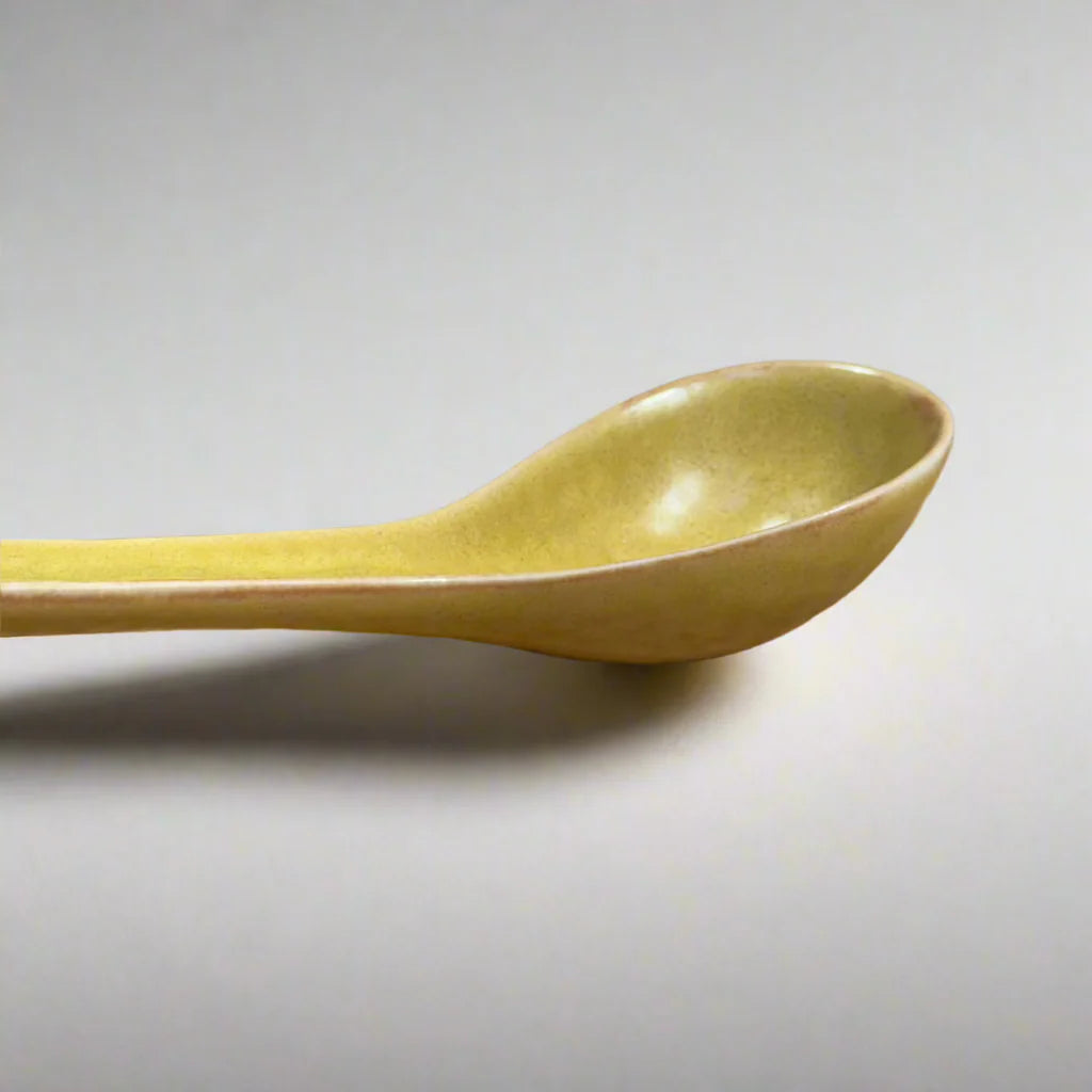 Yellow ceramic spoon on a light gray background