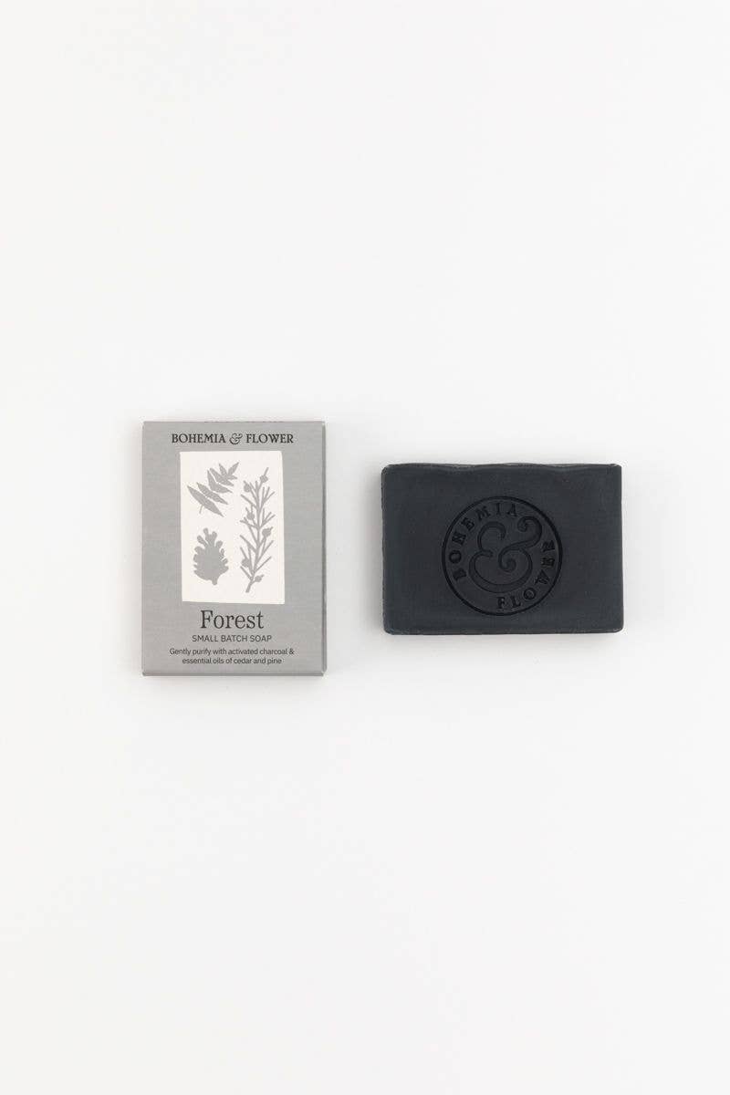 Black soap bar with packaging featuring botanical illustrations on a white background