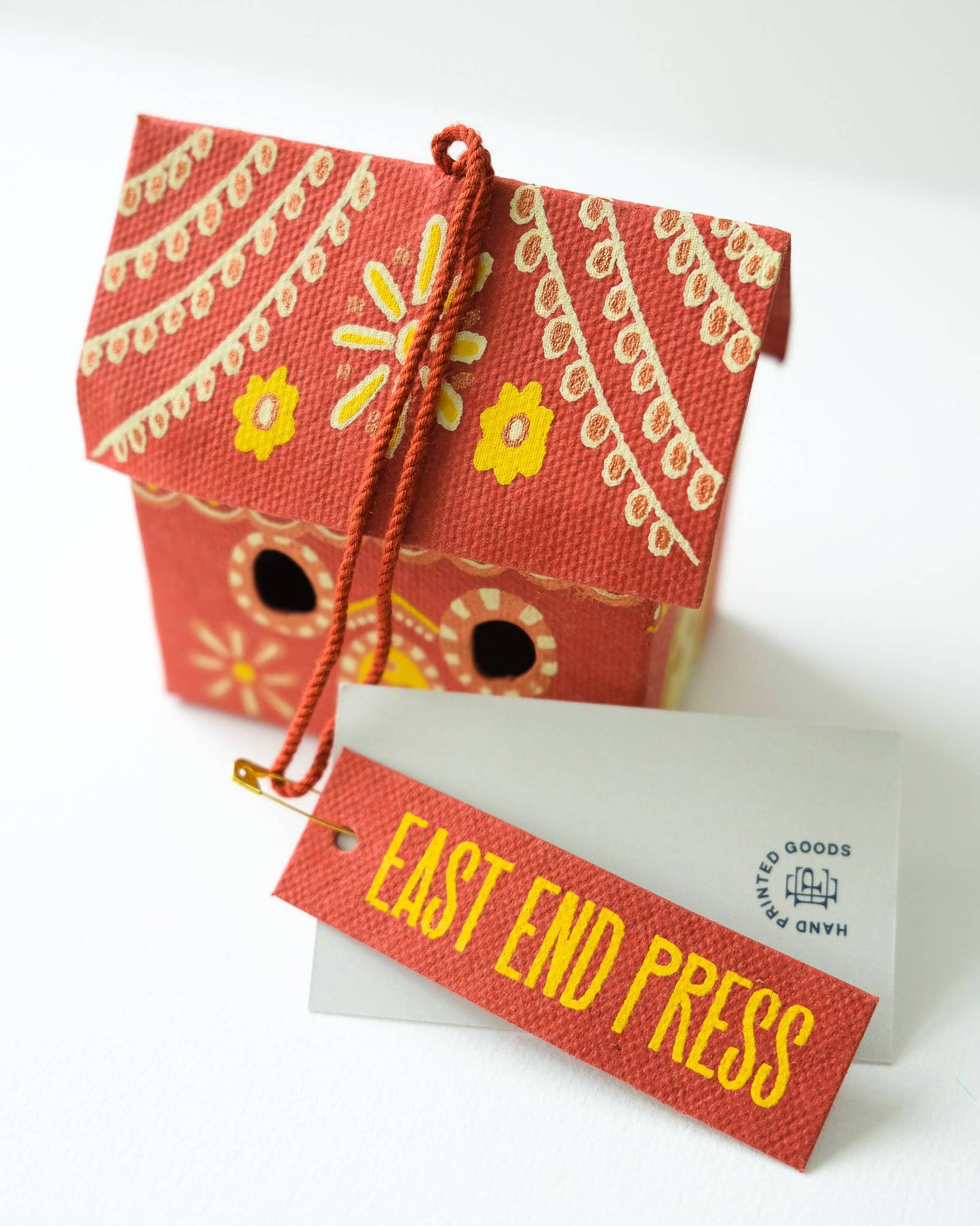 Decorative red box with yellow floral patterns and a 'East End Press' tag on a white background