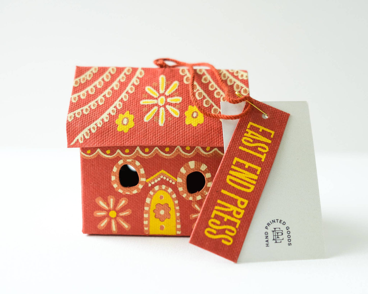 Decorative red house-shaped box with yellow accents and a tag labeled 'East End Press' on a white background.