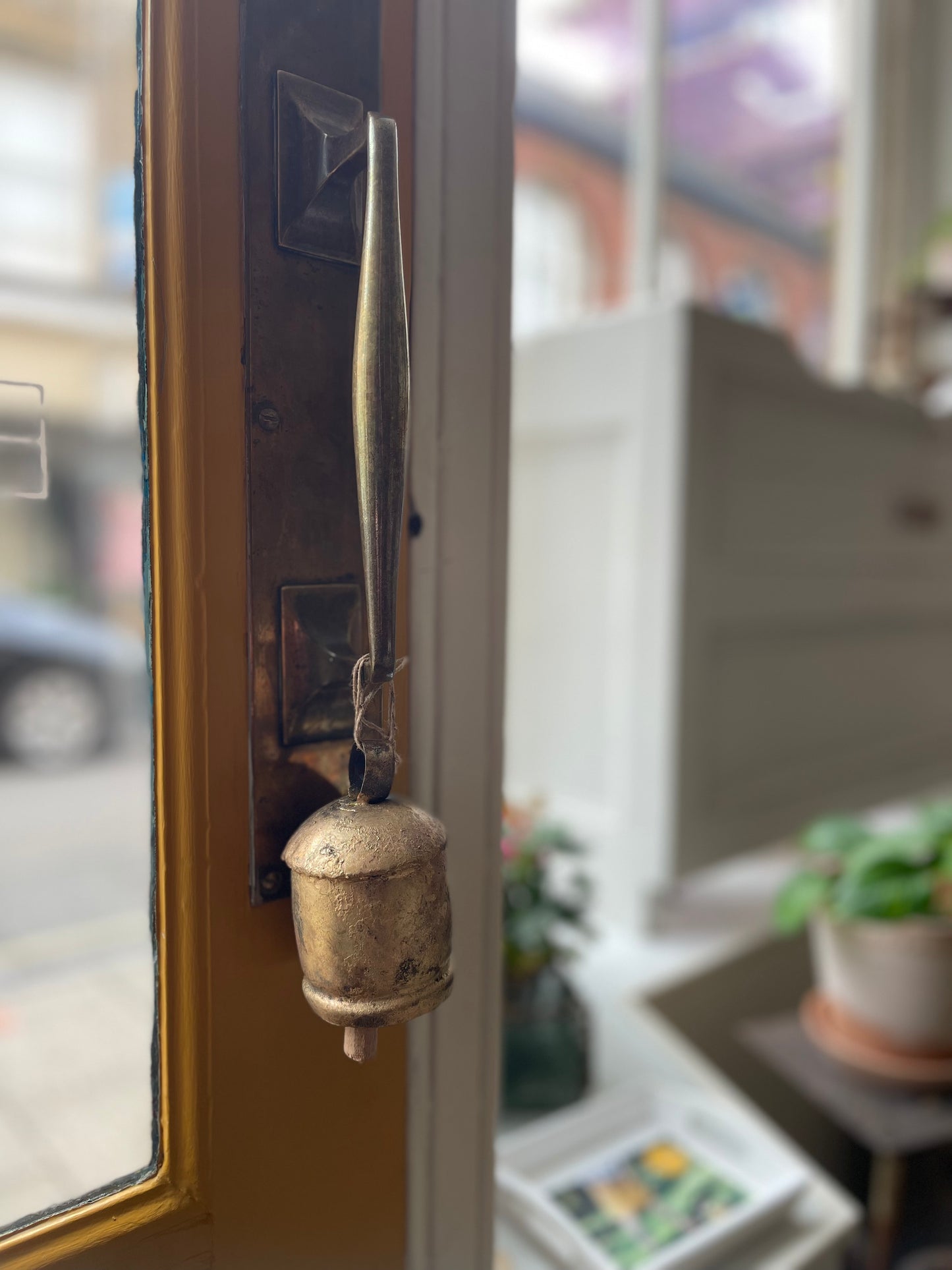 Vintage Noah doorbell on a glass door with a blurred indoor background