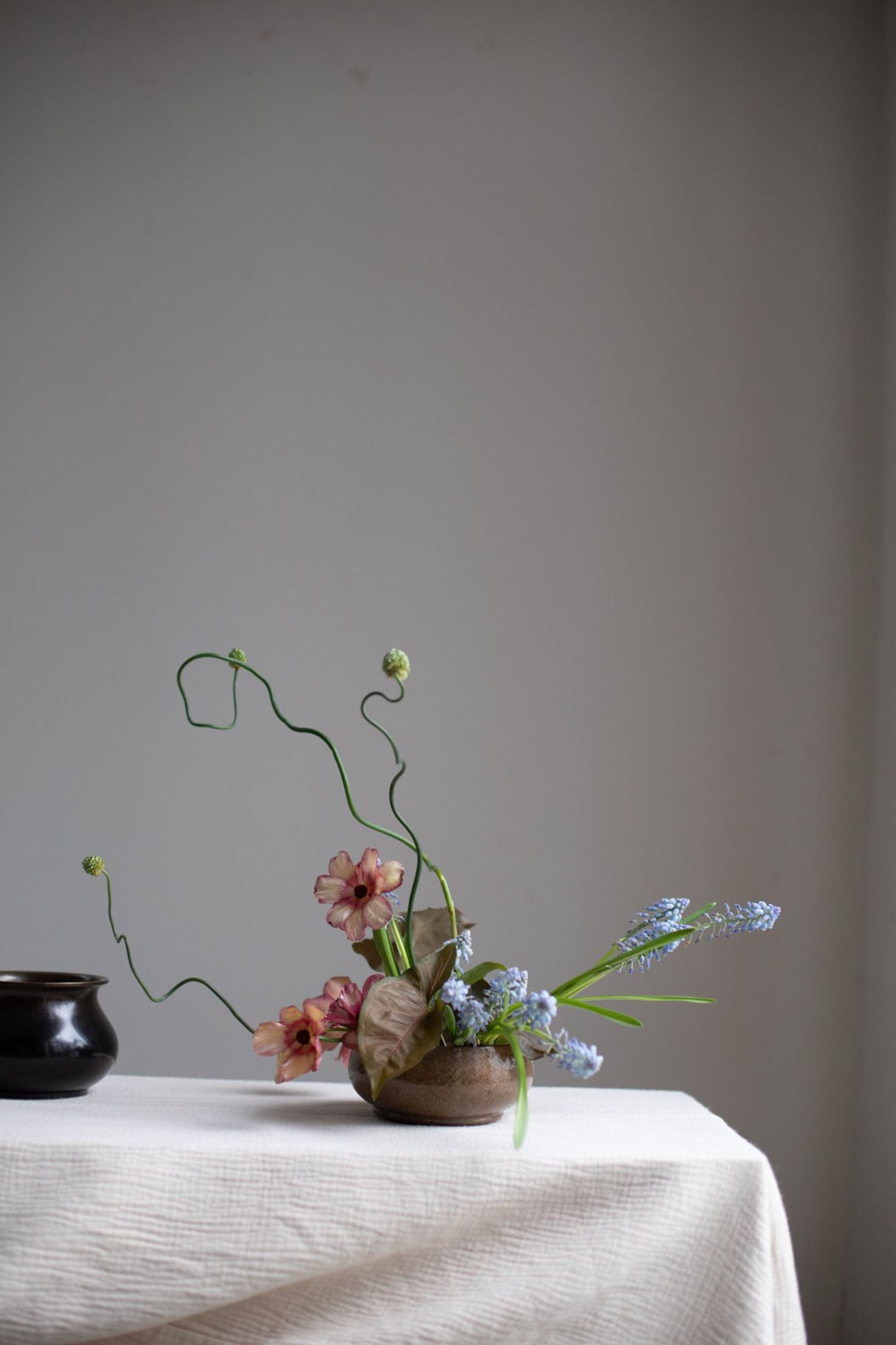 Floral arrangement in a pot on a table with a plain background