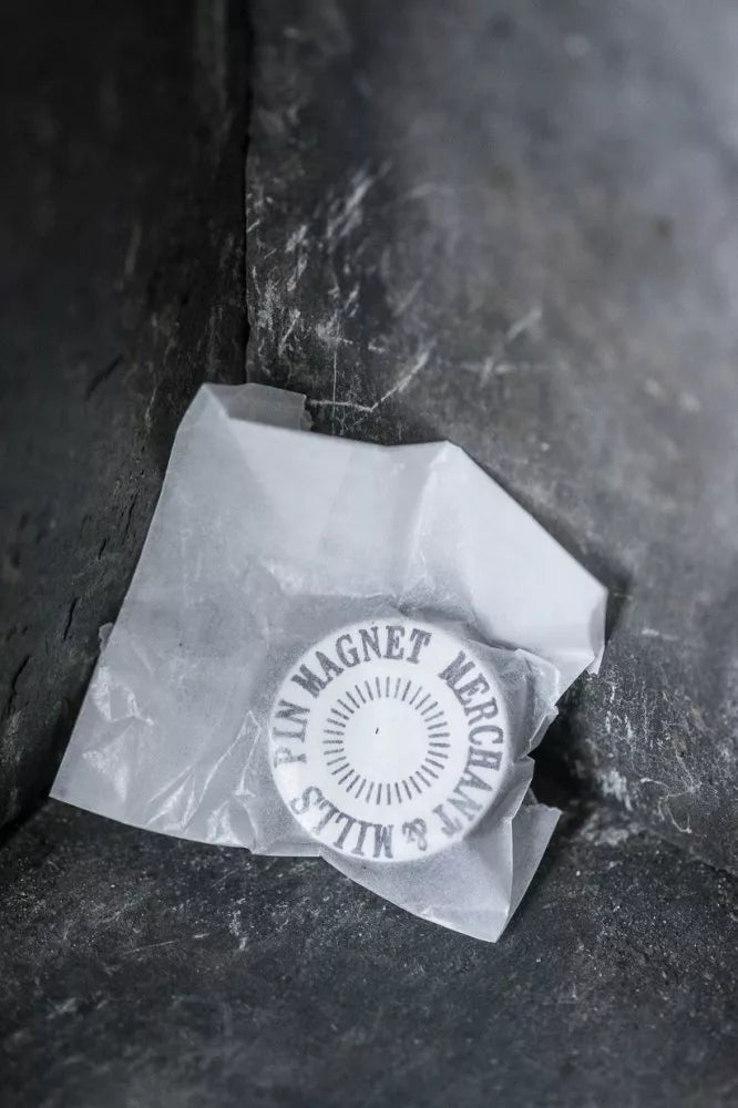 Round pin magnet with text on a piece of paper against a dark background