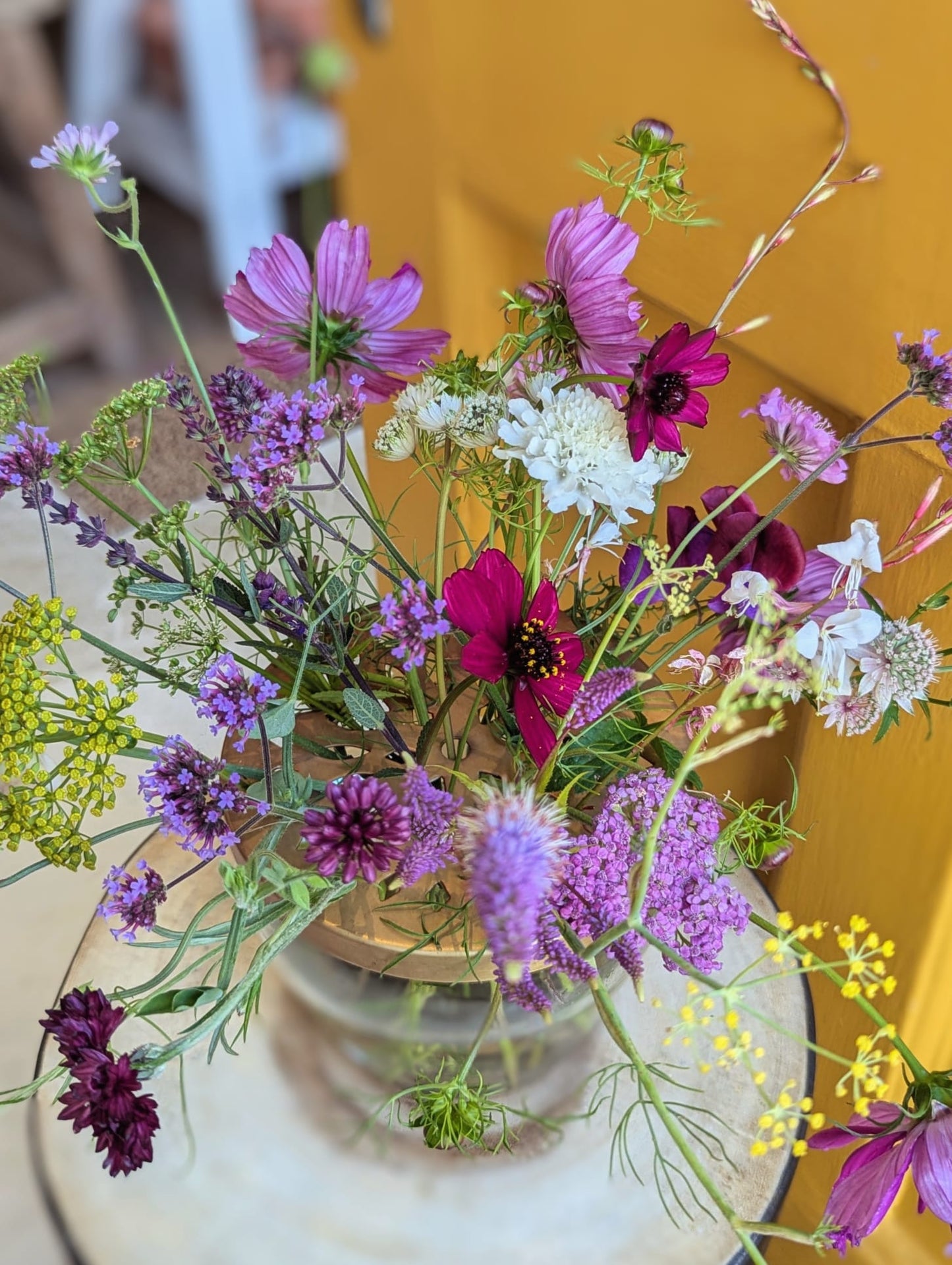 Bouquet of colorful flowers in a clear vase on a yellow background