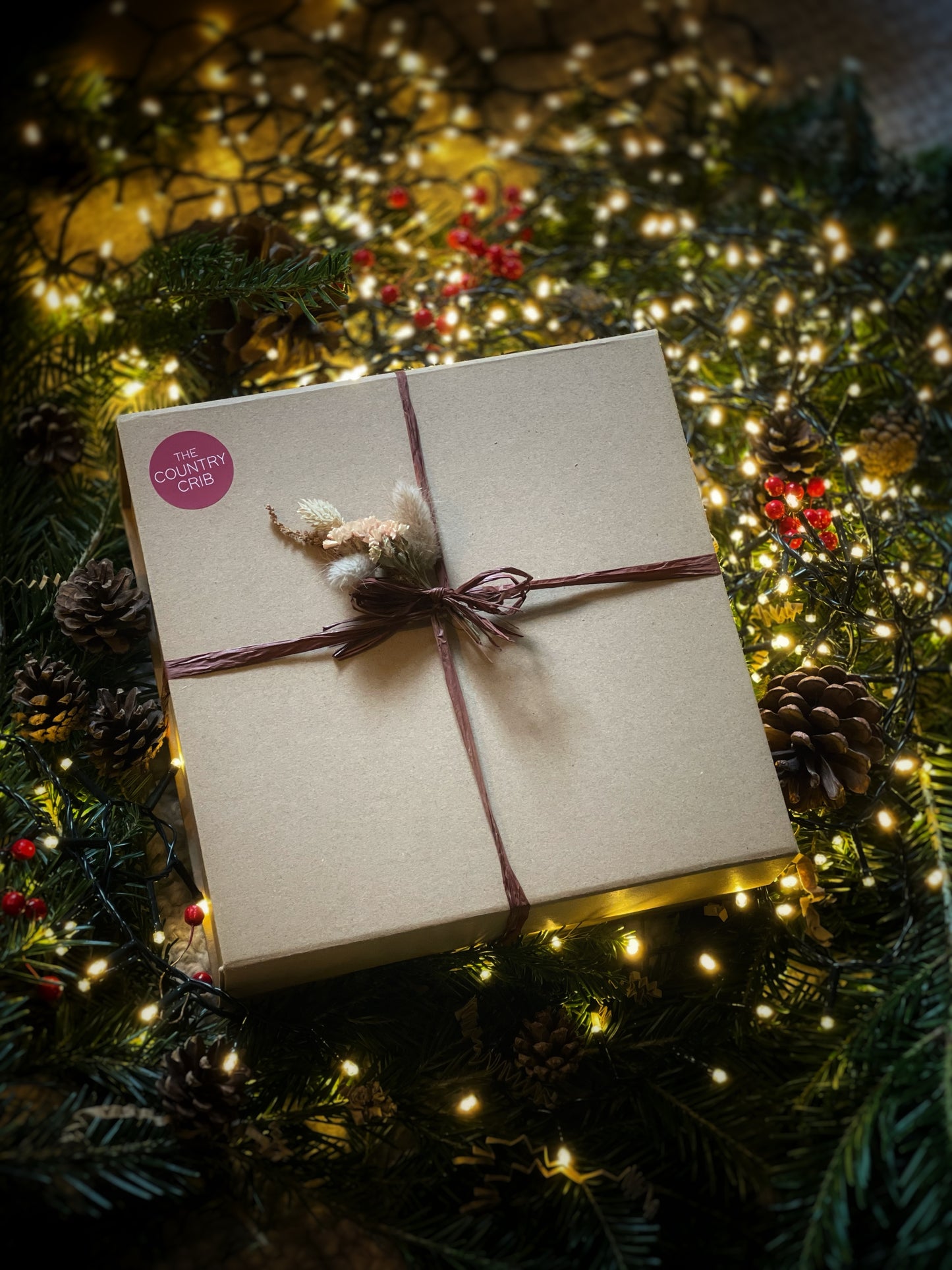 Gift box tied with a ribbon on a Christmas tree with lights and decorations