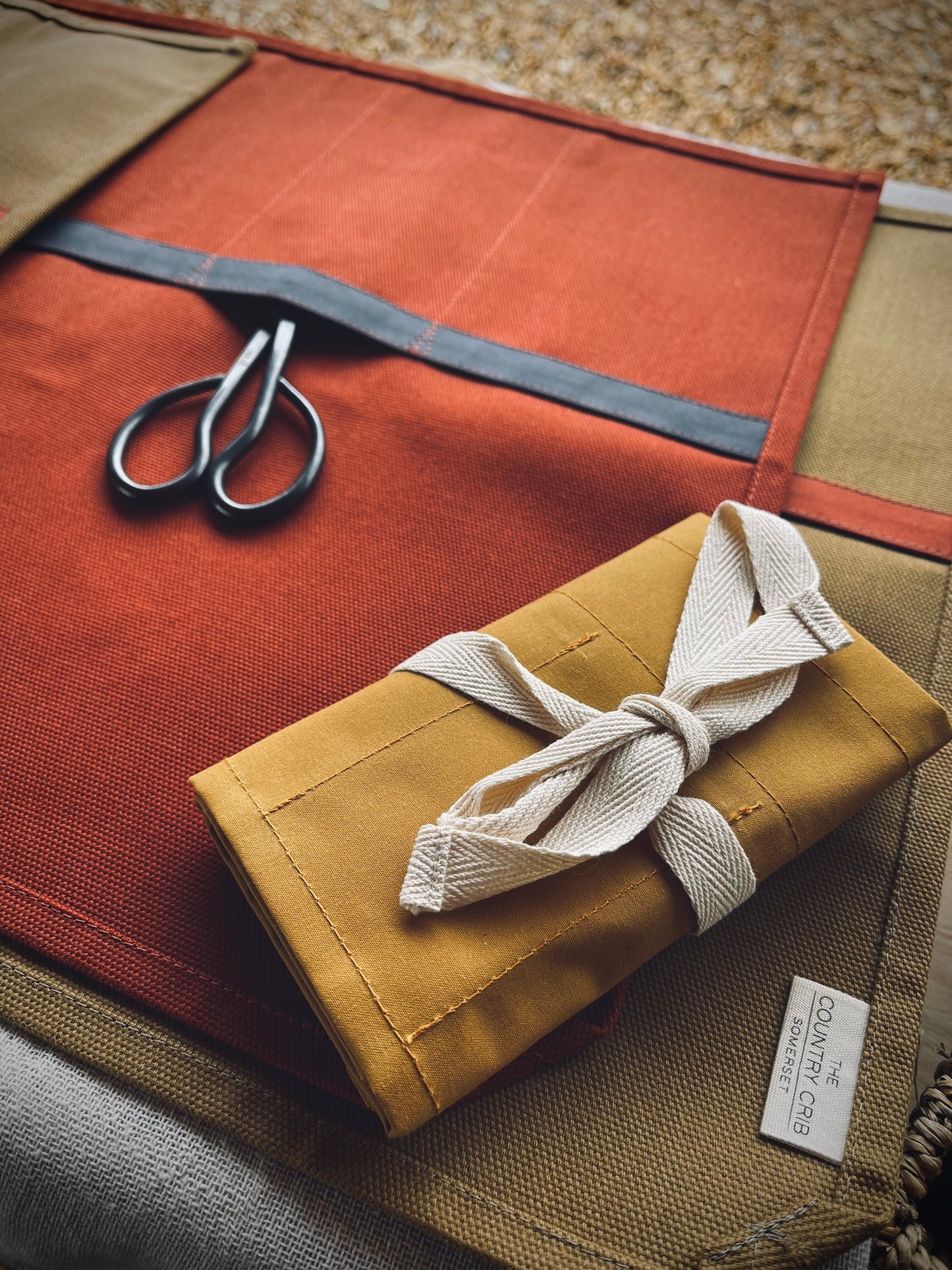 Fabric roll with scissors and a tied package on a textured surface