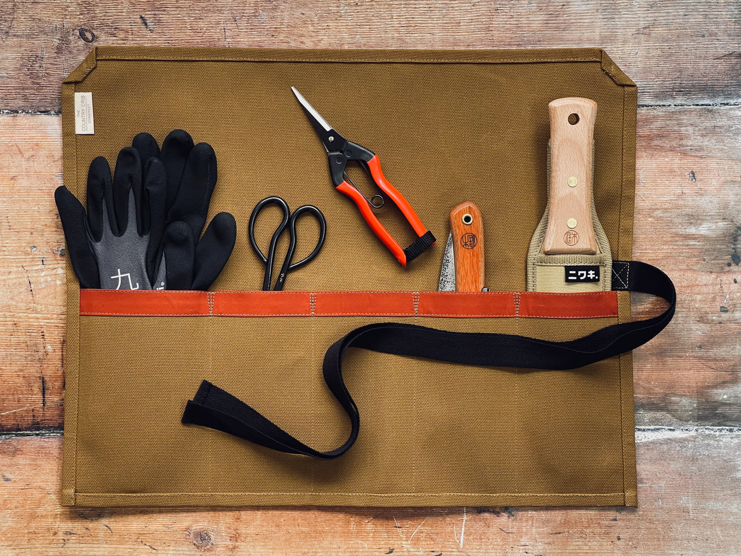 Mustard organic cotton canvas tool roll made by The Country Crib containing gardening tools on a wooden surface