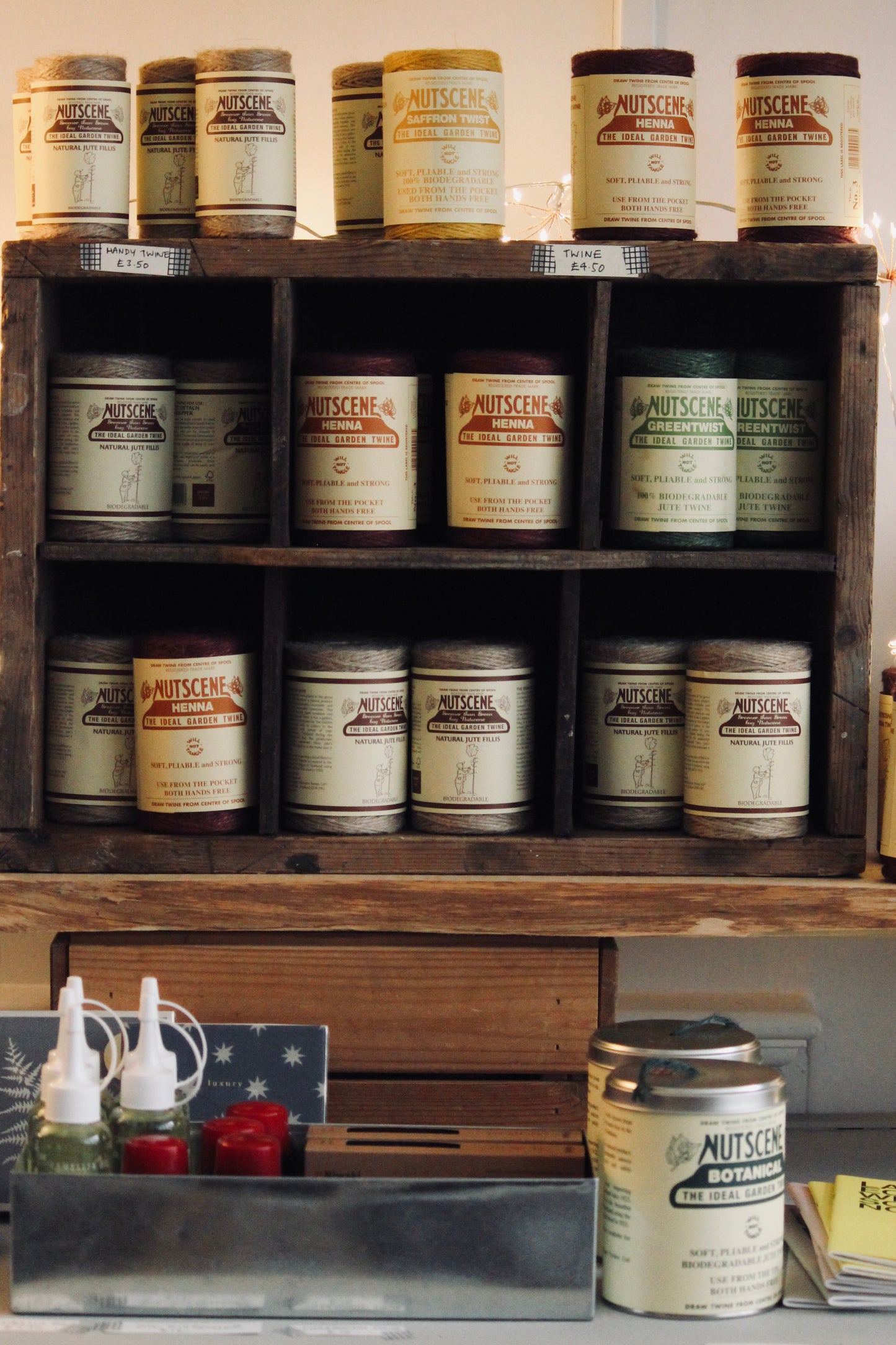 Wooden shelf with various Nutscene jute twines jars and bottles on a wooden surface in The Country Crib shop.