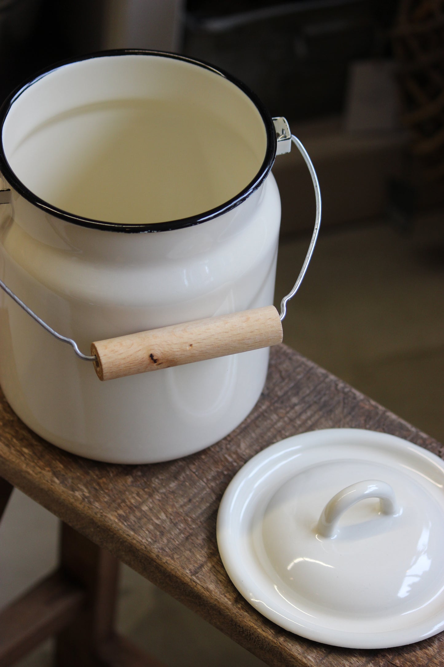 White enamel pot with wooden handle on a wooden surface