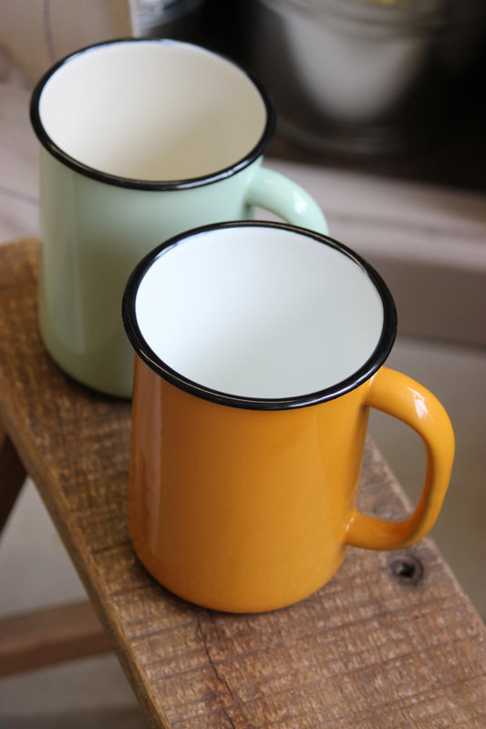 Two jugs, one green and one mustard, with white interior on a wooden surface.