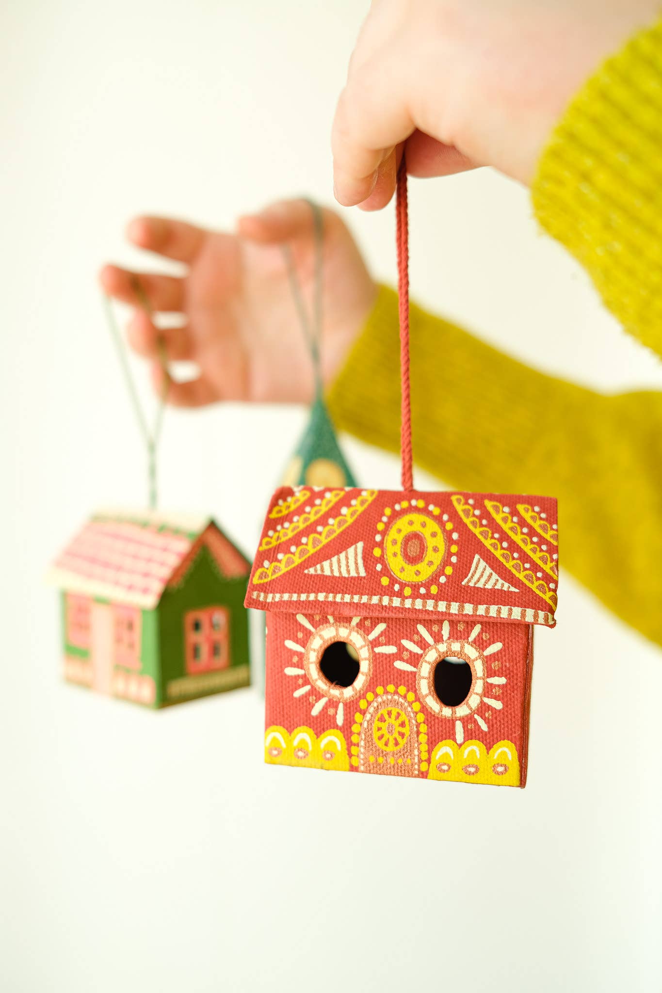 Colorful wooden birdhouses hanging by strings with a blurred background