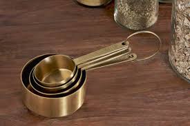 Set of brass measuring cups on a wooden surface