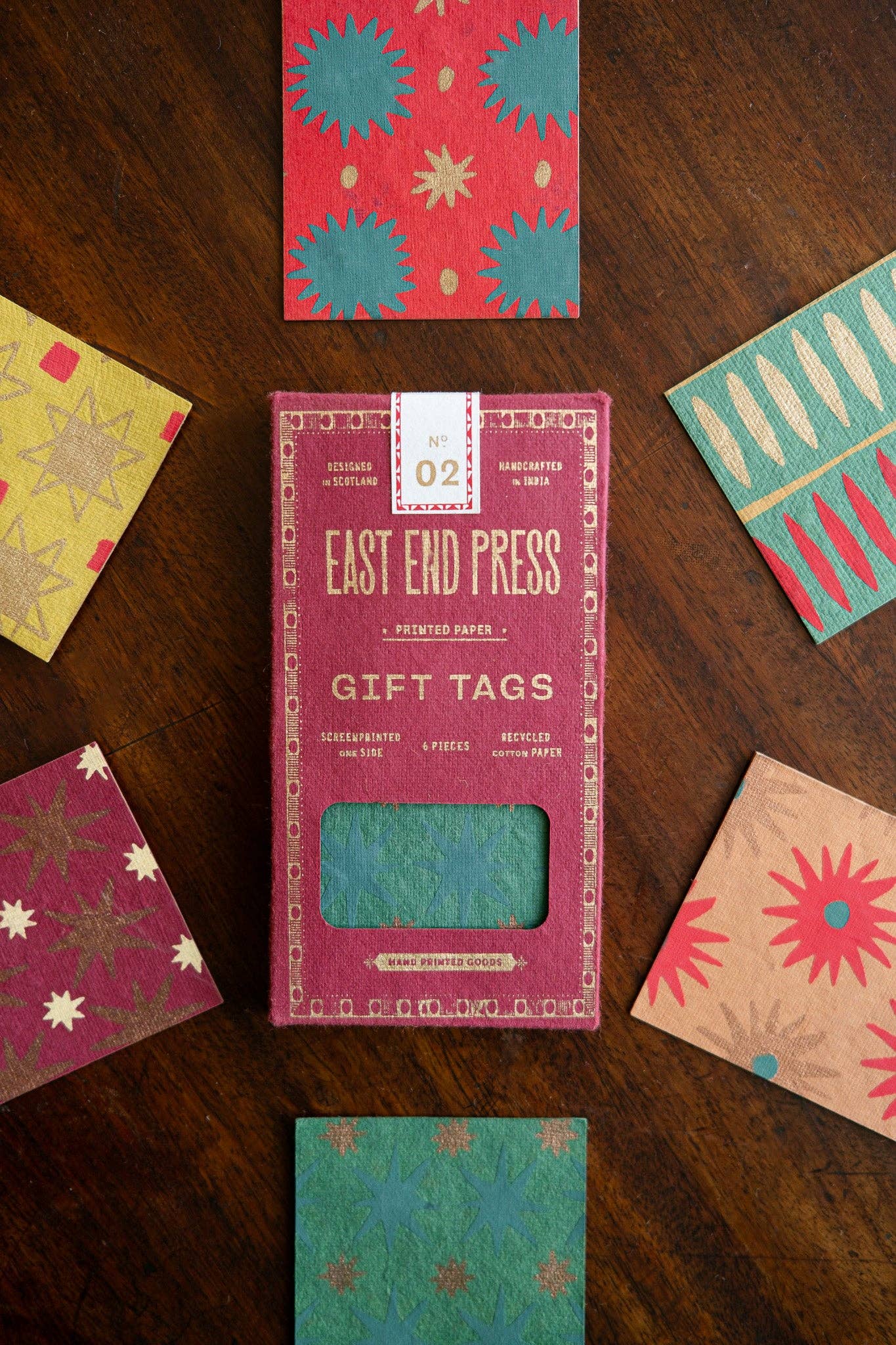 Box of East End Press gift tags with variously designed gift tags on a wooden surface