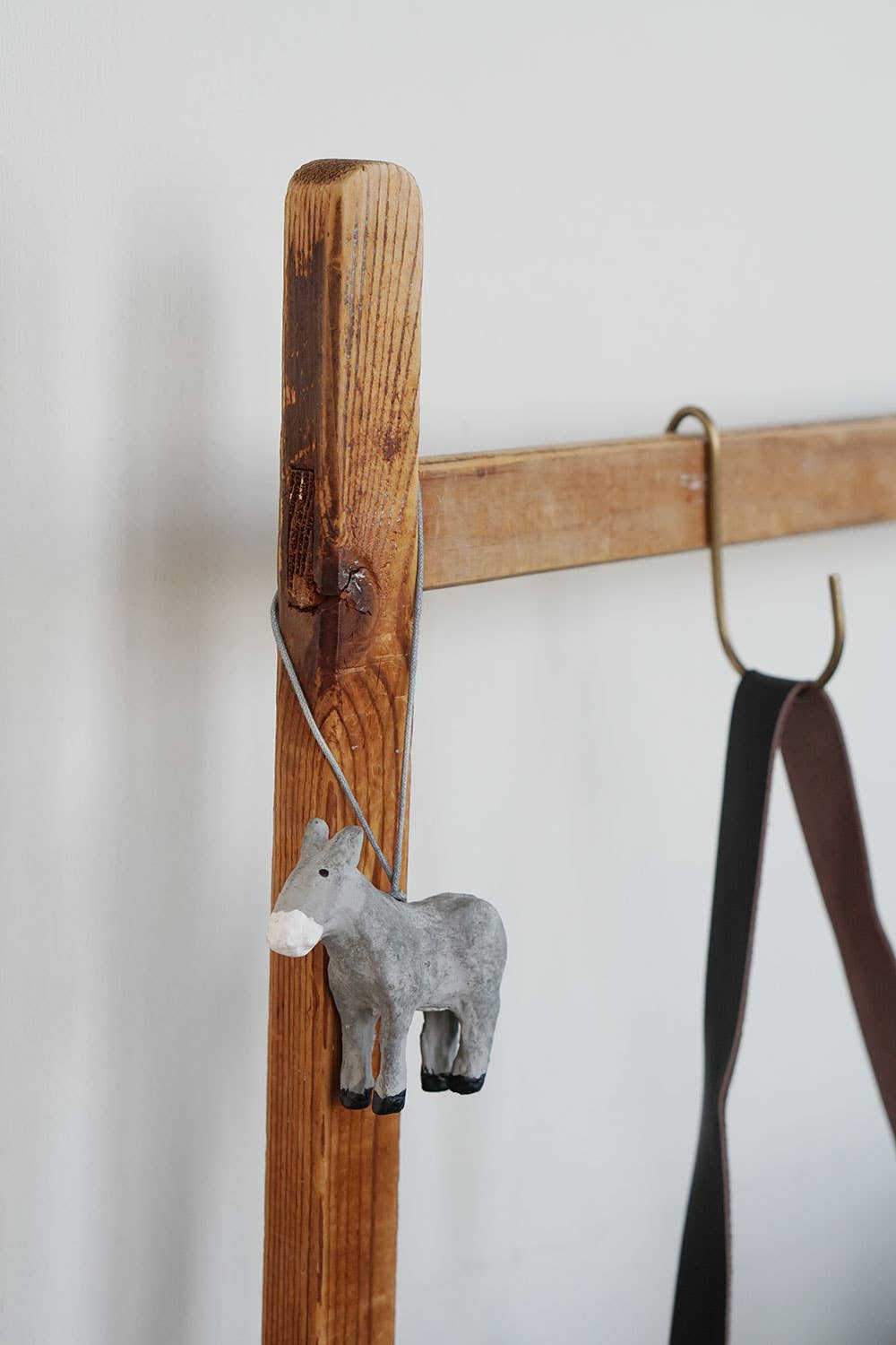 A paper mache grey donkey ornament hung on a wooden post.
