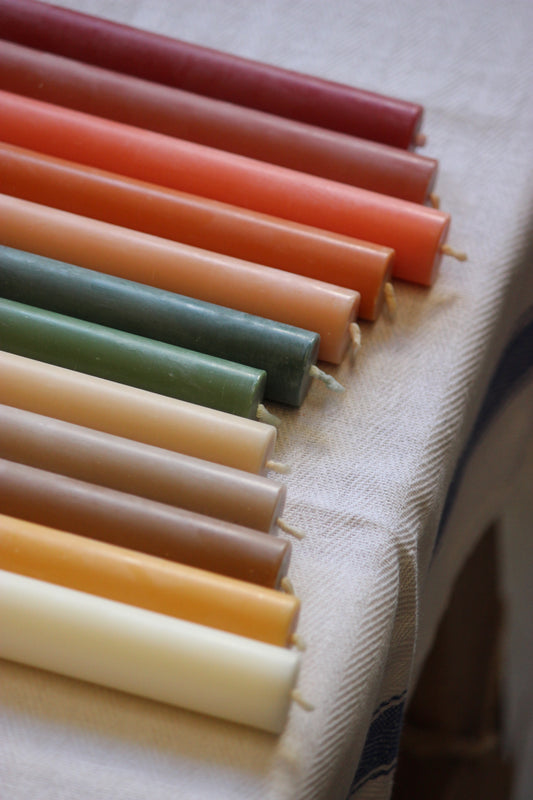 Row of colorful plant based dinner candles on a textured surface