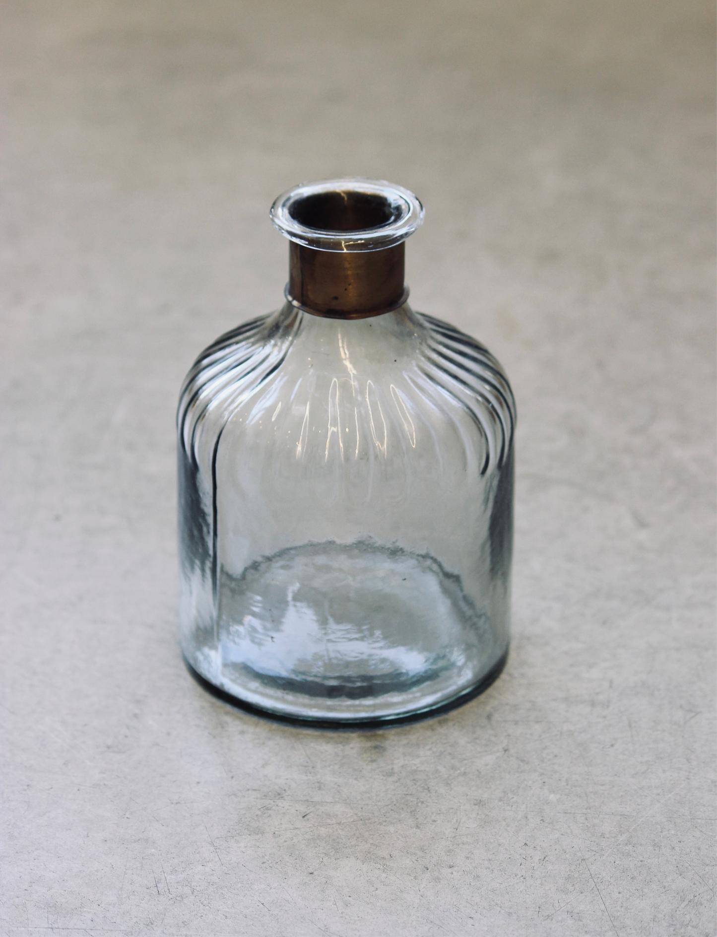 Clear glass bottle with ribbed design on a beige background