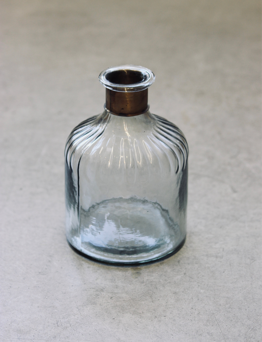 Clear glass bottle with ribbed design on a beige background