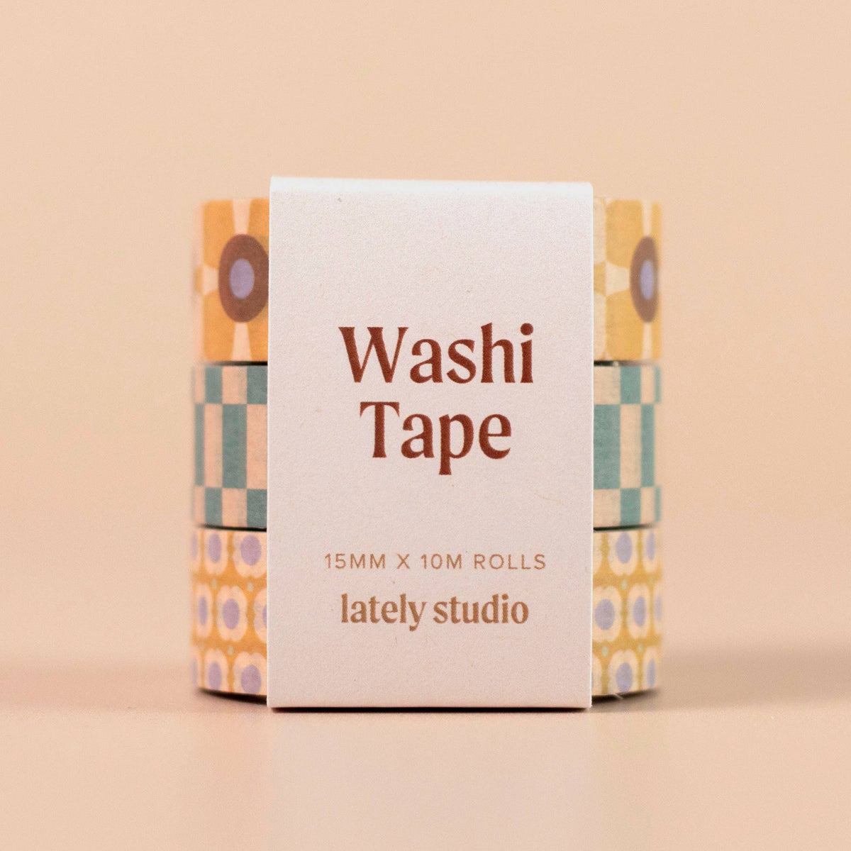 Three rolls of washi tape with retro geometric patterns in yellow, teal, and purple, wrapped in a white paper sleeve labeled 'Washi Tape 15MM X 10M ROLLS lately studio' on a solid beige background.