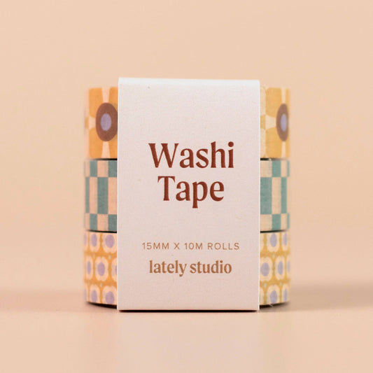 Three rolls of washi tape with retro geometric patterns in yellow, teal, and purple, wrapped in a white paper sleeve labeled 'Washi Tape 15MM X 10M ROLLS lately studio' on a solid beige background.