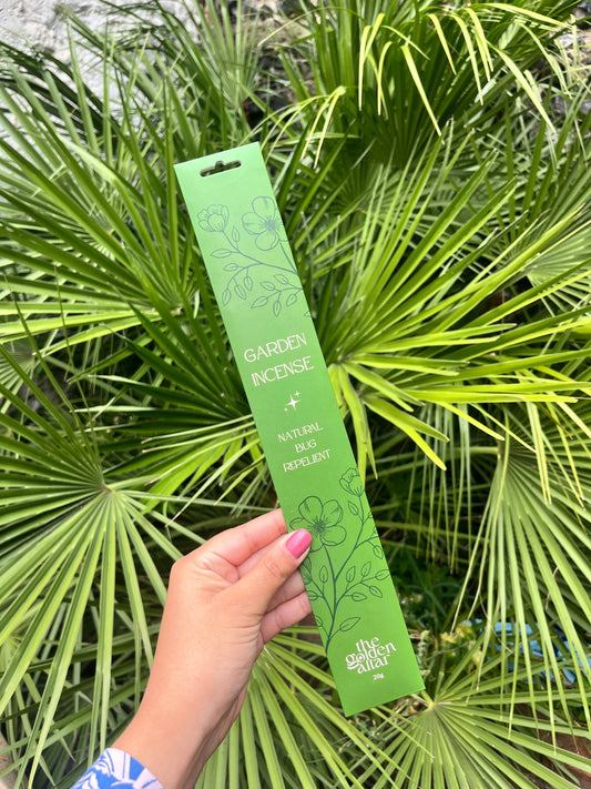 Green garden incense package held in front of green foliage