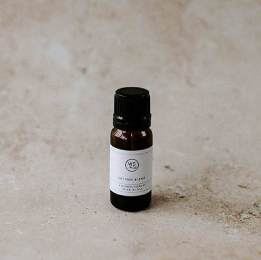 Small brown bottle of Wild Sage Autumn Blend Essential Oils with a black cap on a beige background