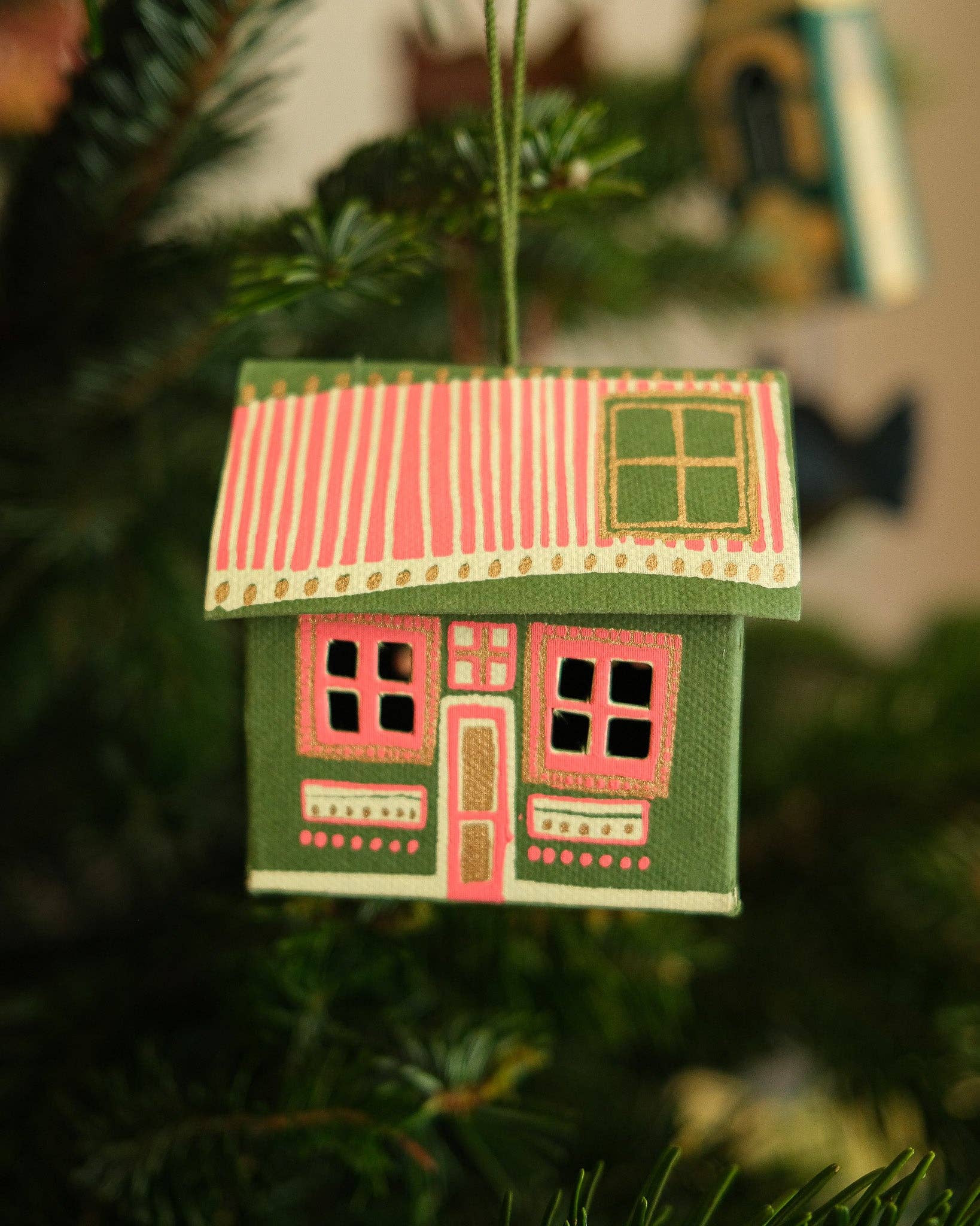 Decorative house ornament hanging on a Christmas tree