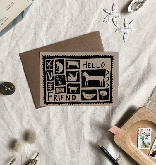 Greeting card with 'Hello Friend' design on a textured surface with stationery items.