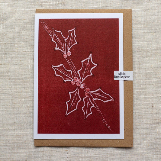 Card with holly design on a red background, featuring the artist's name 'Alicia Breakspear'.