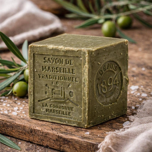 Green soap bar with 'Savon de Marseille' branding on a wooden surface with olive branches.