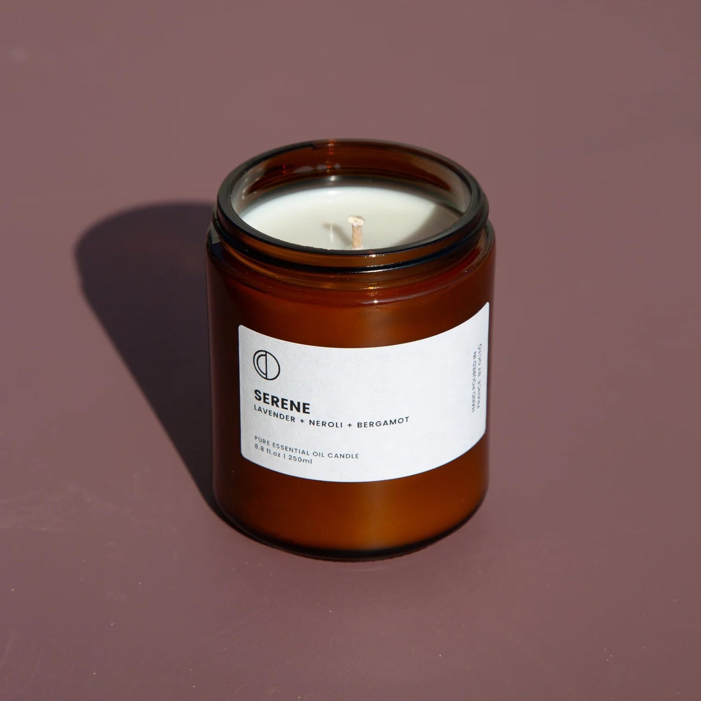Candle in a brown jar with a white label on a dark background