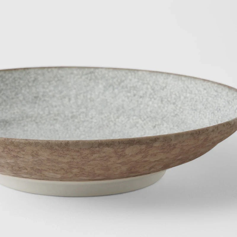 A ceramic bowl with a speckled light gray interior and a textured, earthy brown exterior, shown on a clean light gray background. Ceramic bowl with textured surface on a white background. Crazed Grey Shallow Bowl made in Japan 