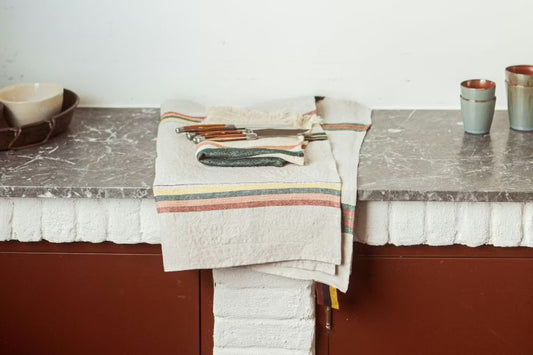Kitchen counter with a towel, knives, and cups on a neutral background