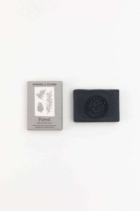 Black soap bar with packaging featuring botanical illustrations on a white background