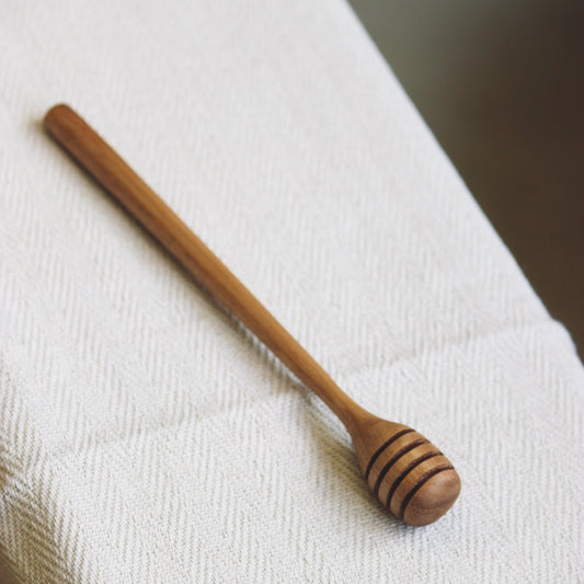 Wooden honey dipper on a white cloth