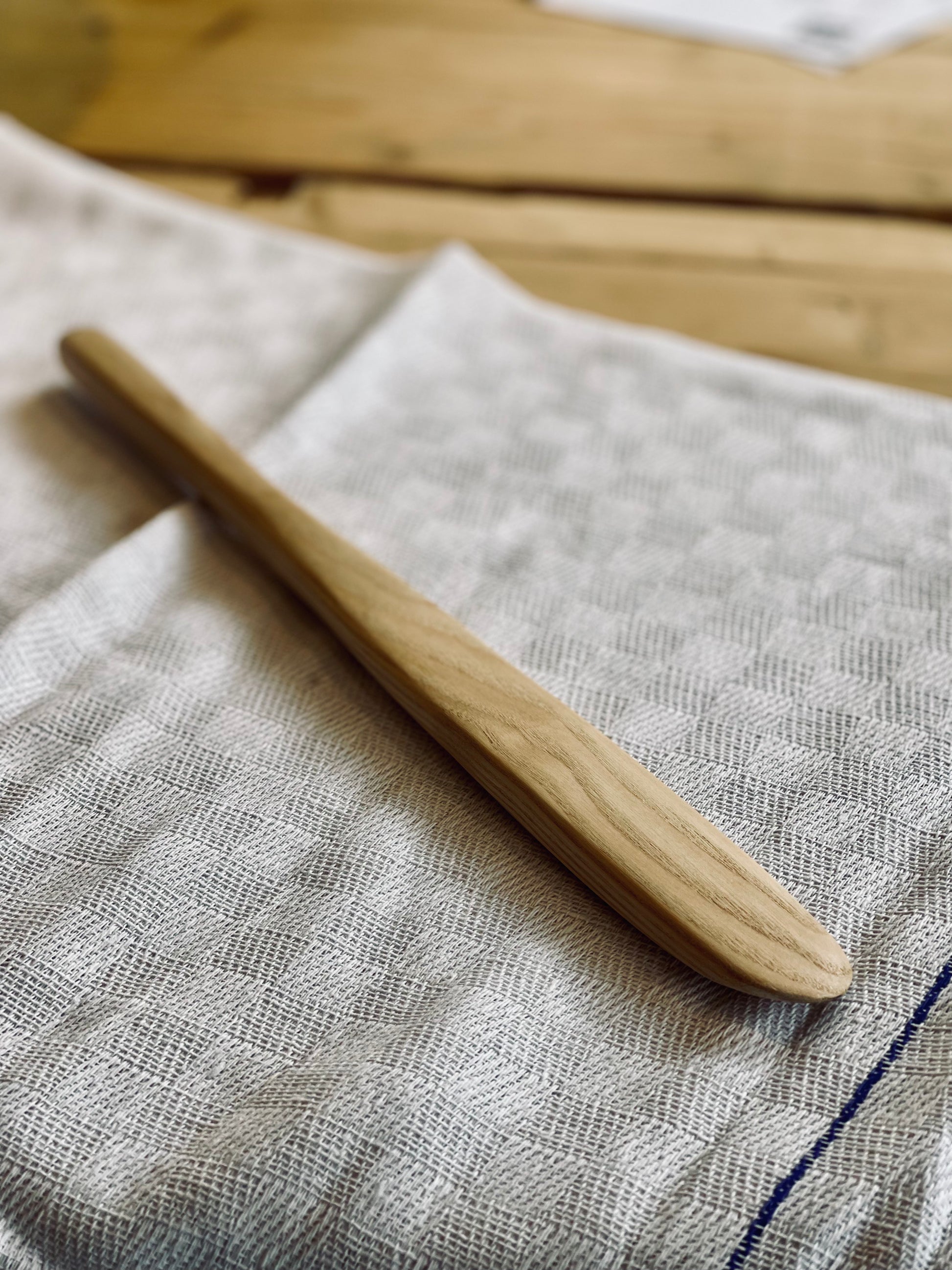 Wooden ash spatula on a textured fabric surface with a wooden background