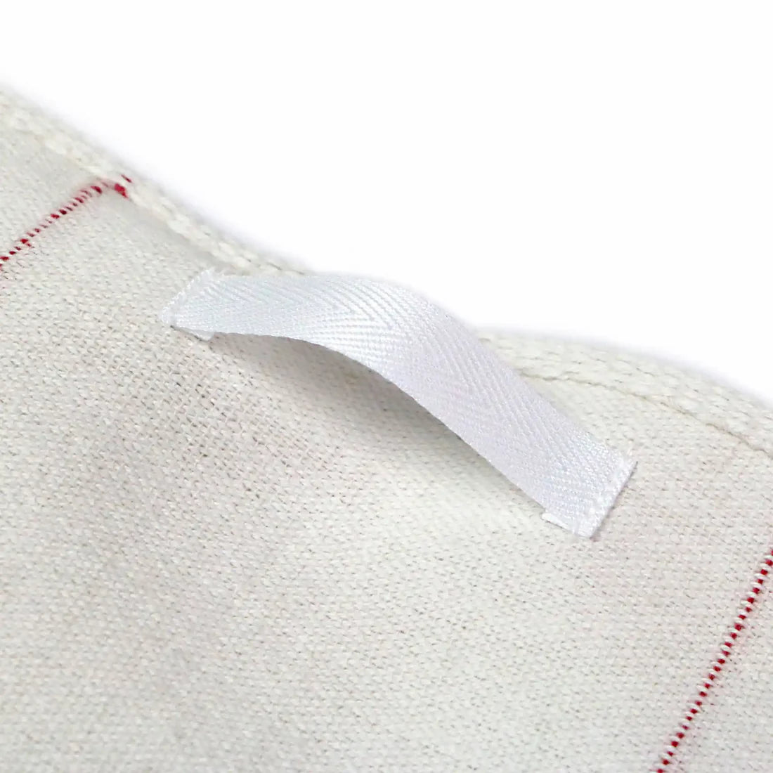 Close-up of a white woven fabric with a red stripe and a white label.