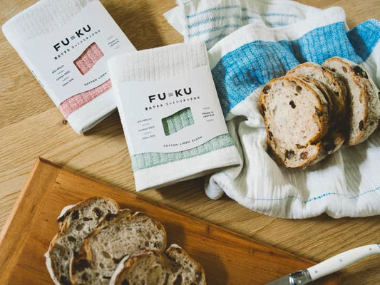 Iori's FU KU Kitchen cloths on a wooden surface with sliced bread, exclusively at The Country Crib.