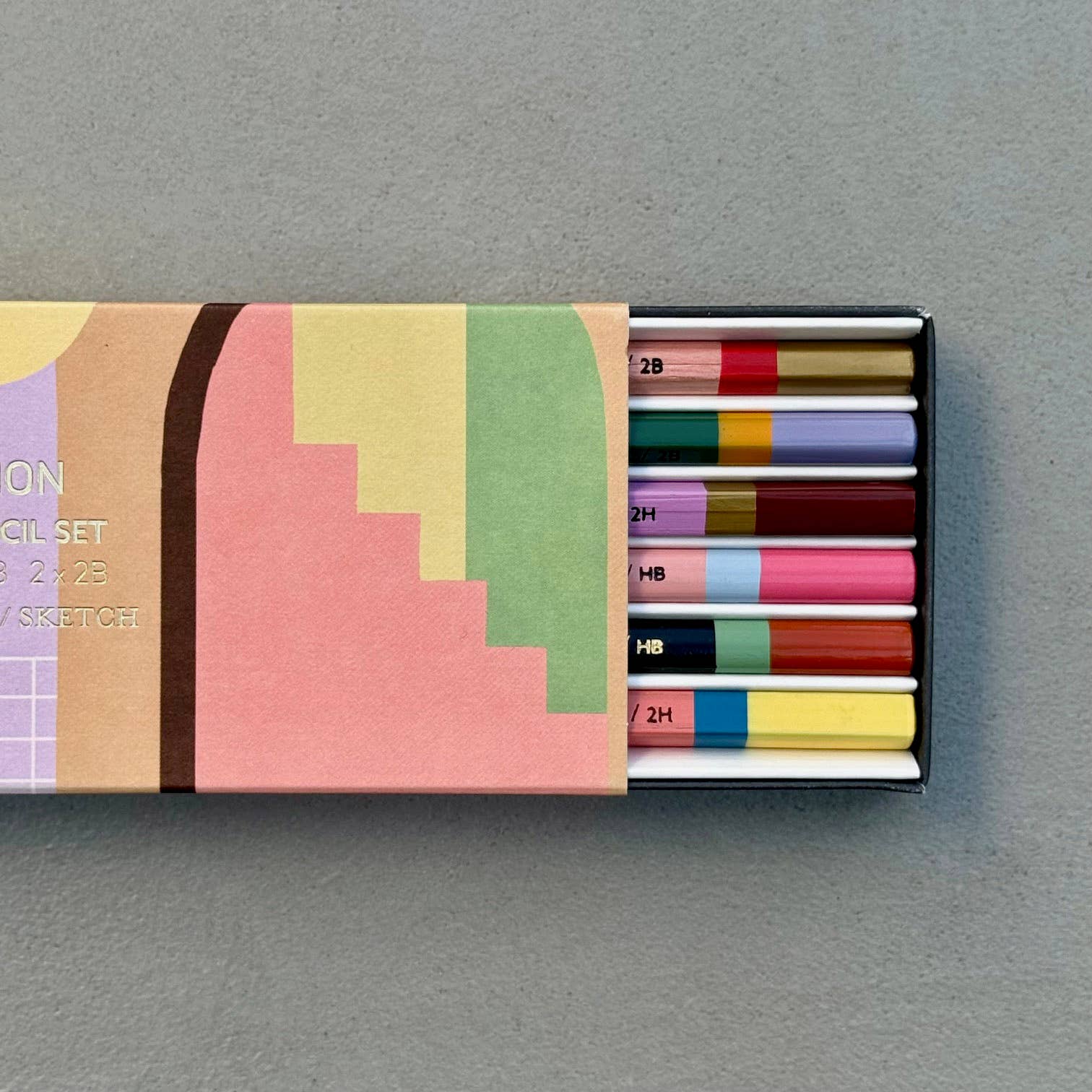 This wonderful 6-piece pencil collection includes 2 square 2H pencils, 2 triangular HB pencils, and 2 hexagonal 2B pencils. Crafted in the UK from sustainably sourced, PEFC-certified wood, each set is presented in a stylish box featuring gold foil accents and a divided tray. Dimensions: 18.5cm x 7cm x 2cm. A perfect gift.