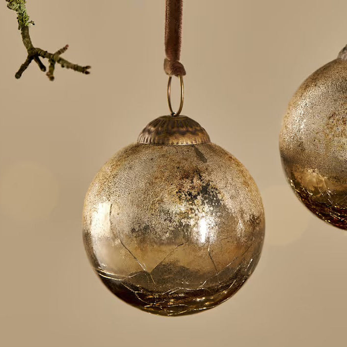 nkuku Gold Crackle Konara bauble gold glass ornaments hanging against a beige background
