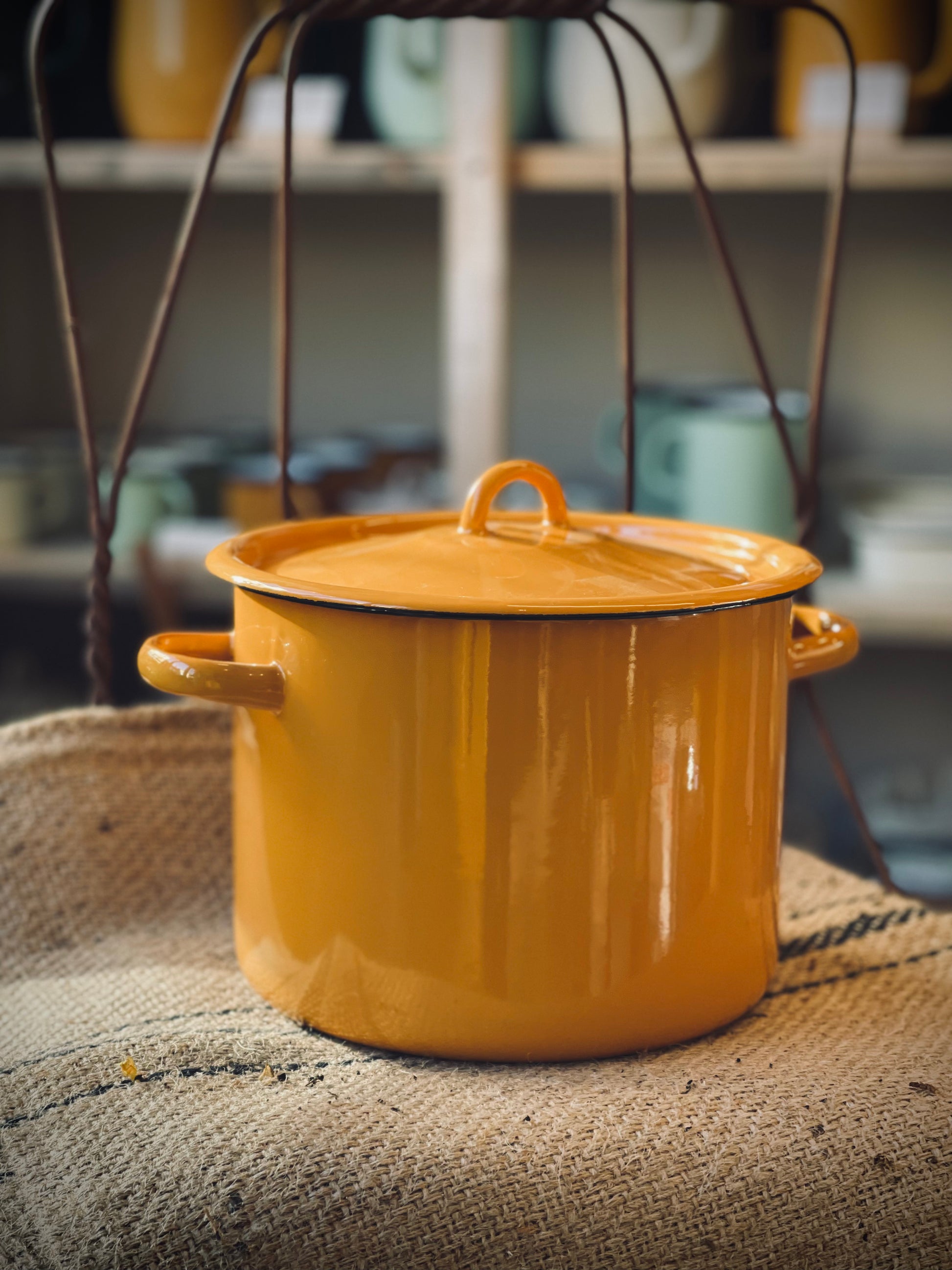 Yellow enameled pot with handles on a textured surface