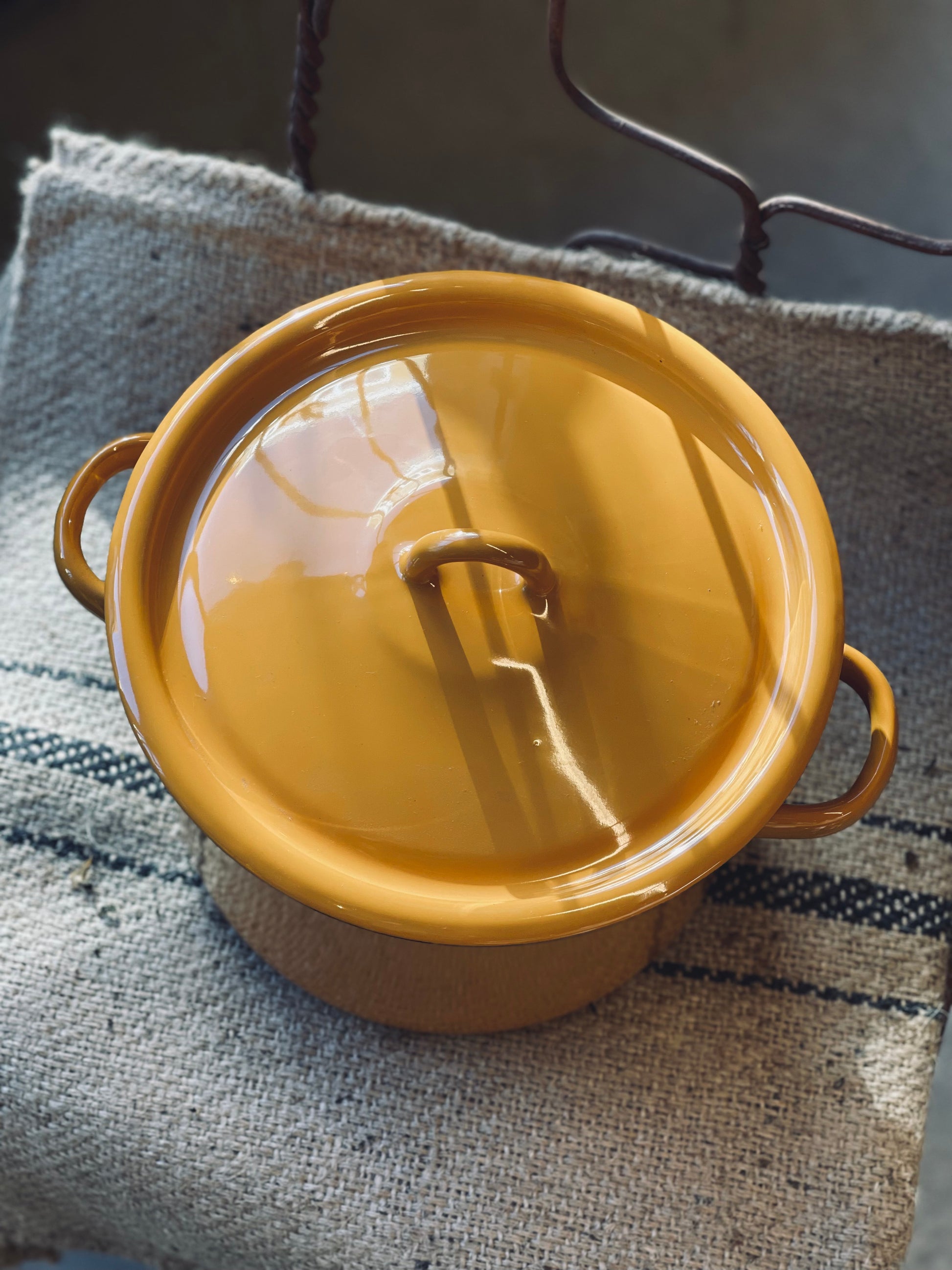 Yellow pot with a lid on a textured surface