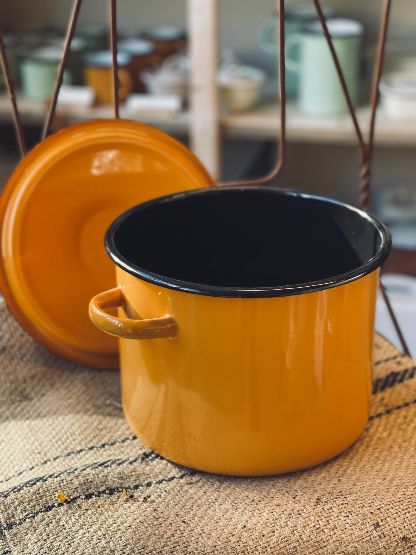 Yellow enameled pot with black interior on a textured surface
